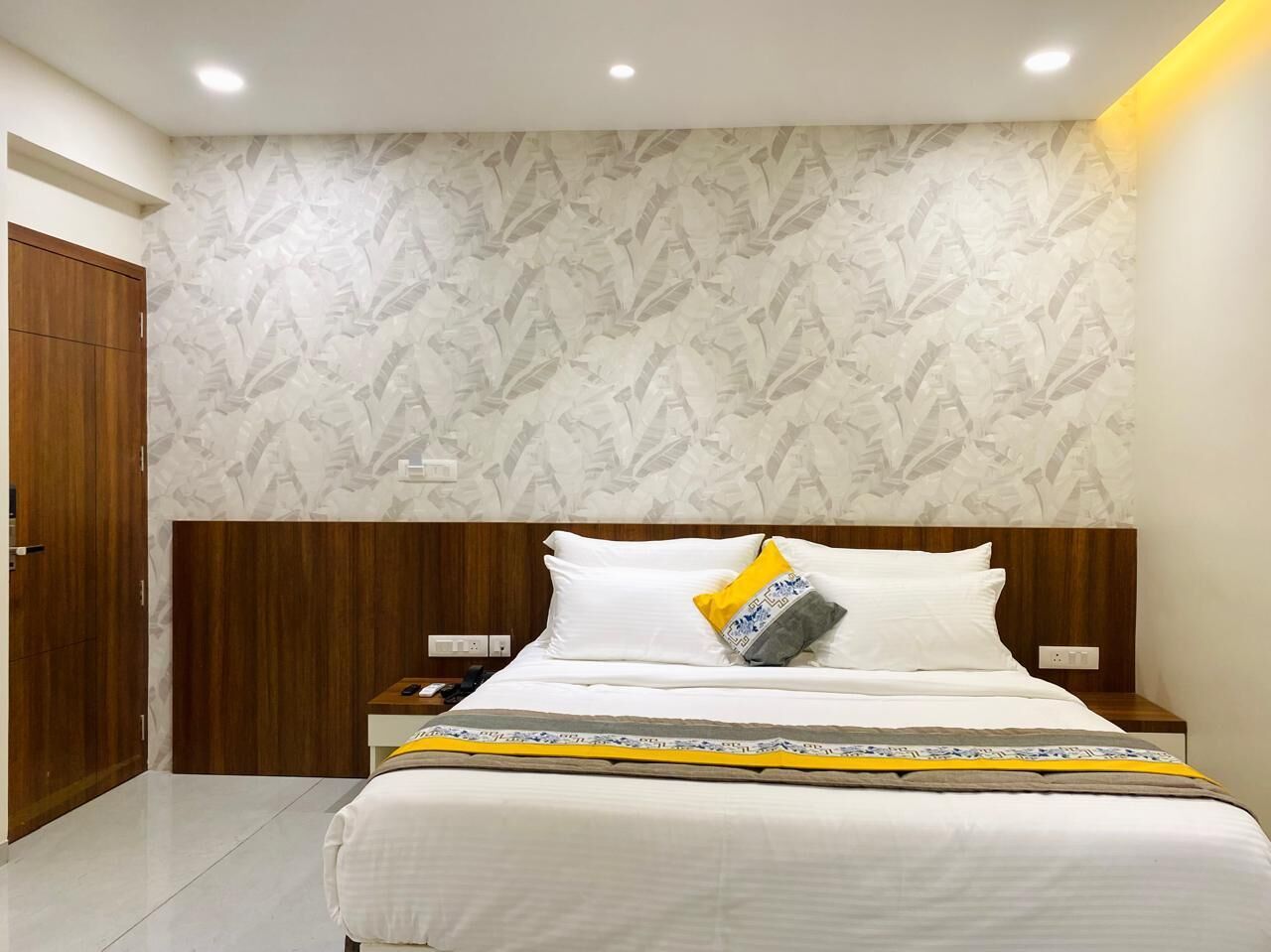 Een keurig opgemaakt slaapkamer met een bed, houten hoofdeinde en een behang met patroon.