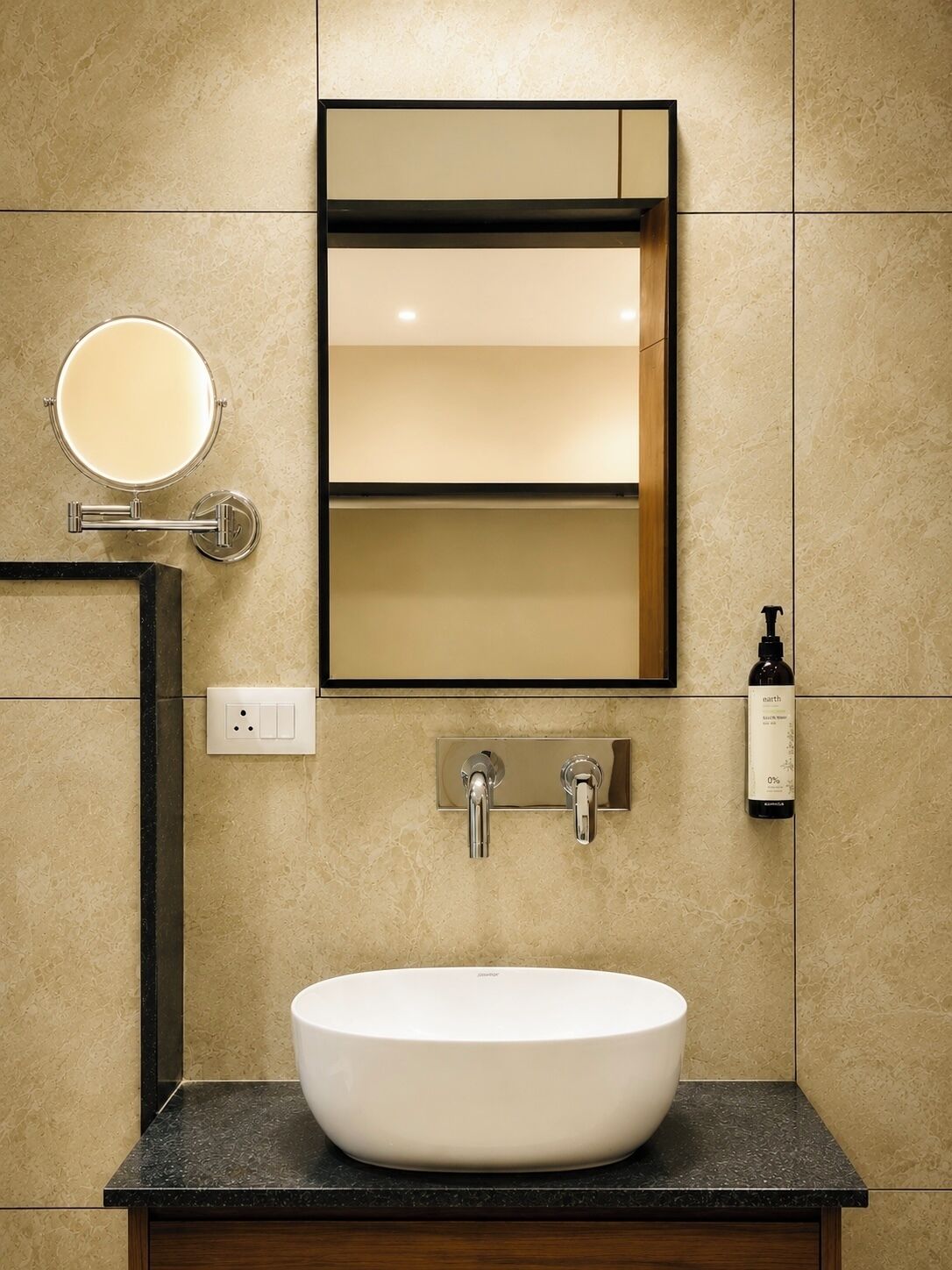 Un baño con un lavamanos blanco, un espejo y una botella de jabón.