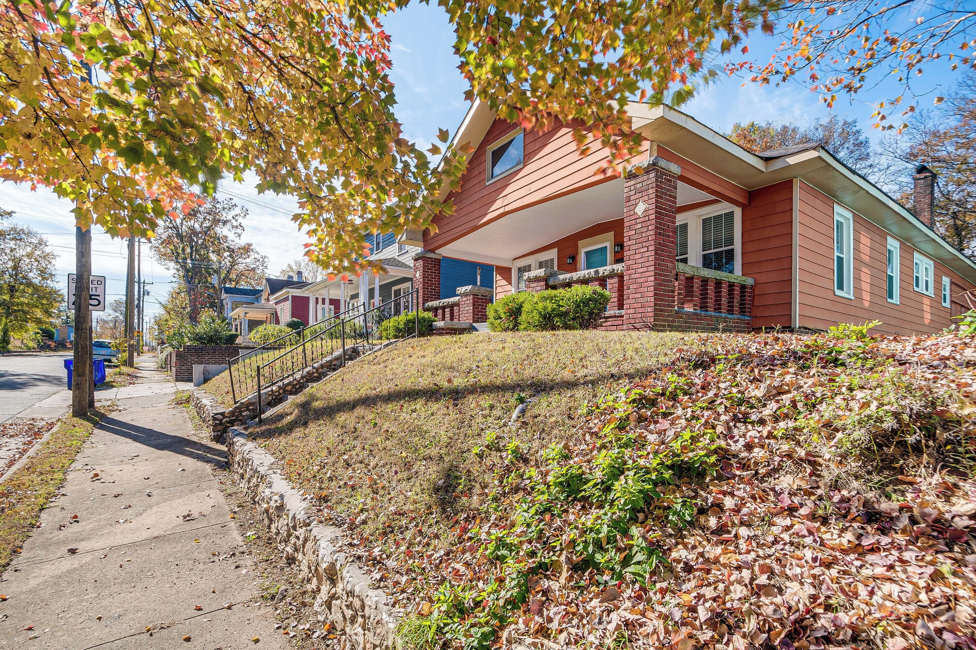 A two-story house with a brick facade, a front porch, and a small front yard with a stone retaining wall.