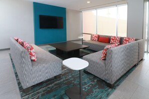A modern living room with grey sofas, a white coffee table, and a flat-screen TV mounted on a blue wall. - Avid Hotel Fresnillo (Fresnillo)