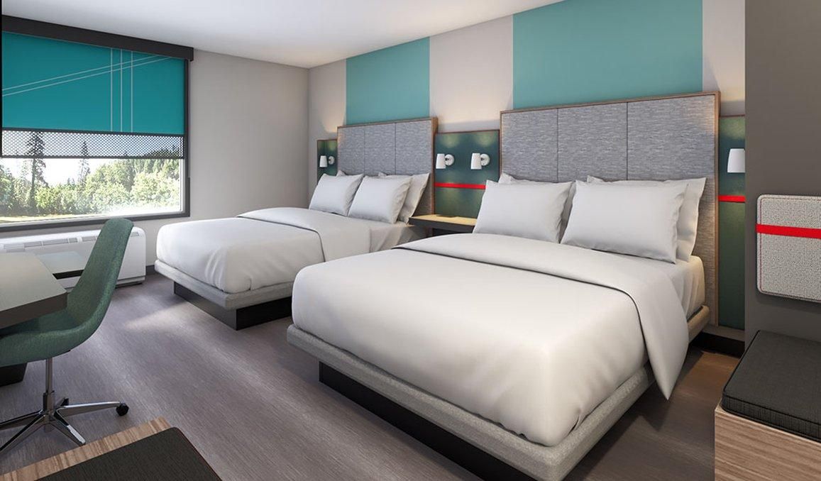 A hotel room with two beds, a desk, a chair, and a window with a view.