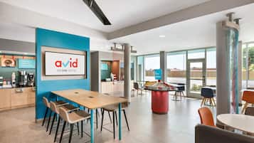 Un moderno vestíbulo de hotel con recepción, área de descanso y amplios ventanales que ofrecen vistas.