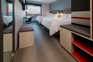Una habitación de hotel moderna con dos camas, un escritorio y un banco.