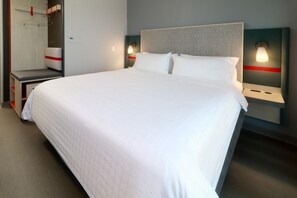 A hotel room with a large bed, bedside tables, a wardrobe, and wall-mounted lamps. - Avid Hotel Fresnillo (Fresnillo)
