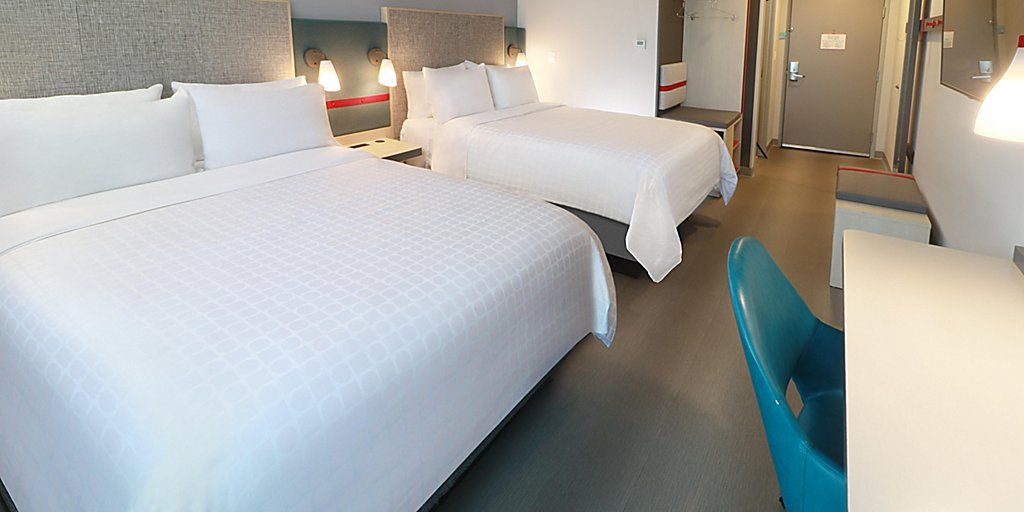 A hotel room with two beds, a desk, and a chair.