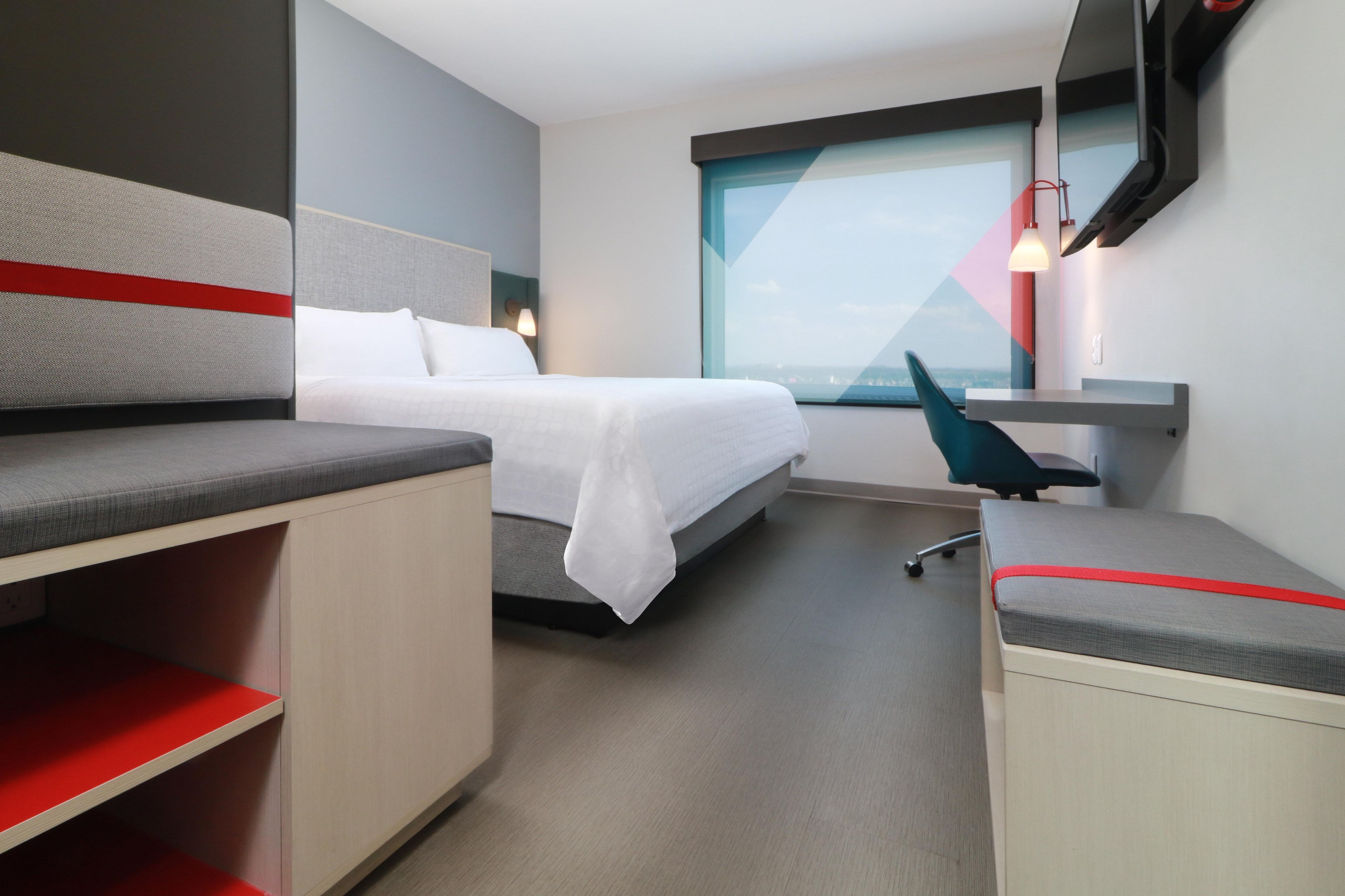 Una habitación de hotel moderna con una cama, un escritorio y una silla.