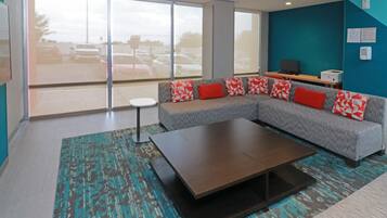A modern living room with a sectional sofa, a coffee table, and a view of a parking lot through large windows.