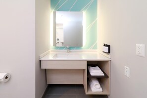 A modern bathroom with a sink, mirror, towel rack, and toilet paper dispenser. - Avid Hotel Fresnillo (Fresnillo)