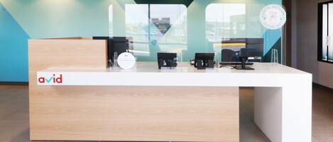 A reception desk with a logo, a red pendant light, and a glass partition.
