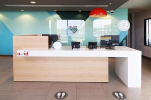 A reception desk with a logo, a red pendant light, and a glass partition. - Avid Hotel Fresnillo (Fresnillo)