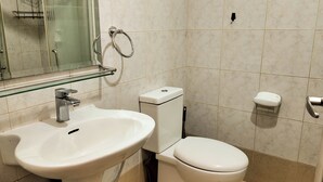 Et badeværelse med hvid vask, toilet og brusekabine i glas.