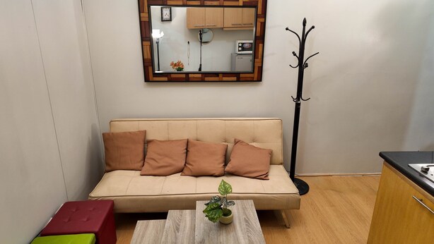 En hyggelig stue med en beige sofa, et træbord og en potteplante.