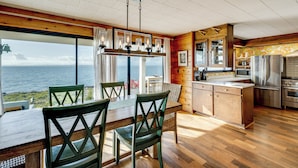 Una cocina moderna con una isla grande, suelo de madera y vista al océano.