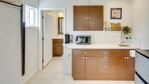Una cocina con armarios de madera, microondas, cafetera y lavamanos.