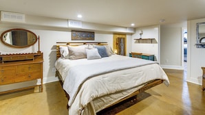 A bedroom with a large bed, wooden dresser, and a mirror. - Peaceful Patio View! Waterfront Puget Sound Unit (Poulsbo)