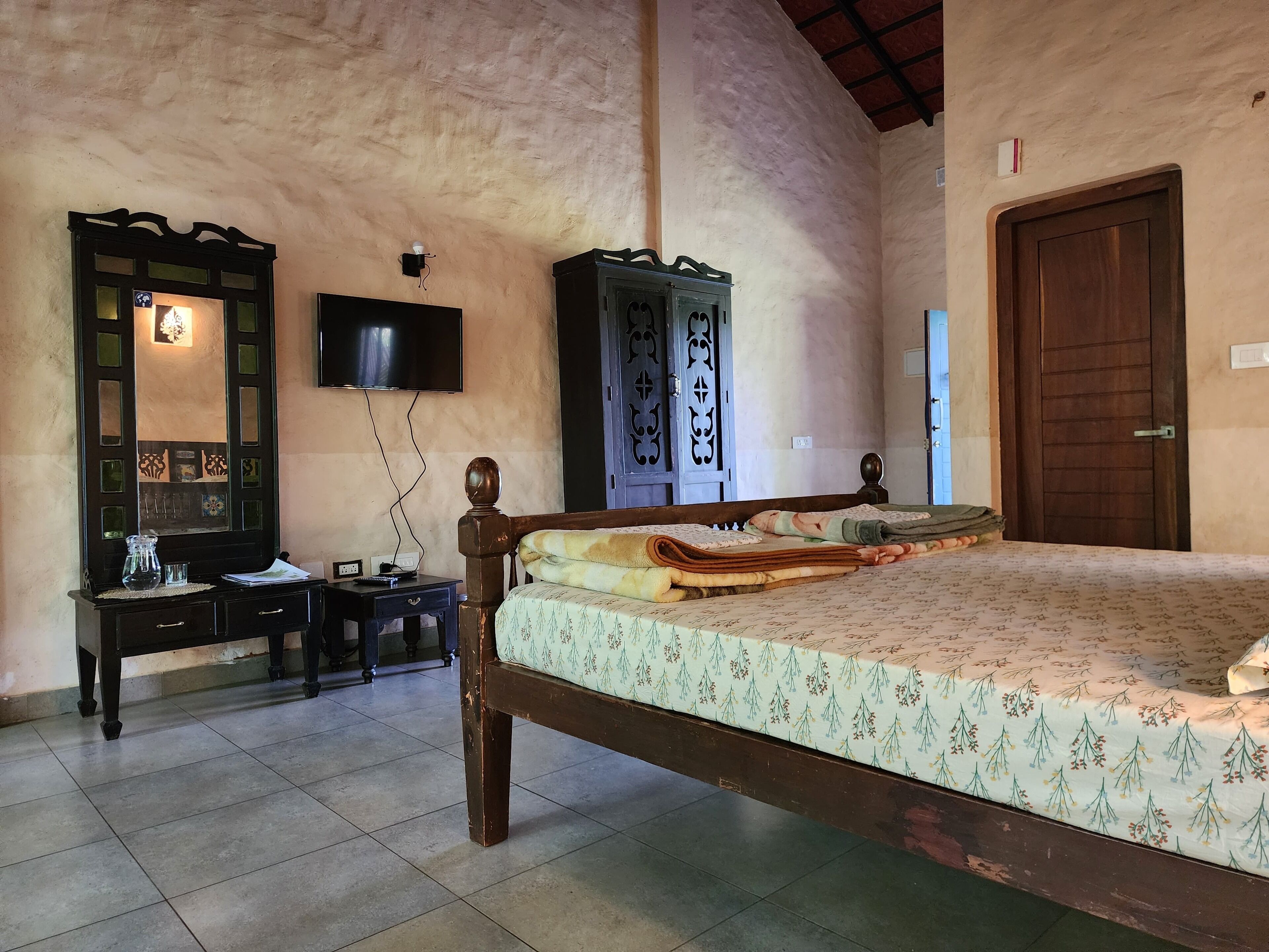 A bedroom with a bed, a dresser, a television, and a door.