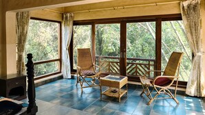 Ein Zimmer mit großen Fenstern, Korbmöbeln und einem Fliesenboden.