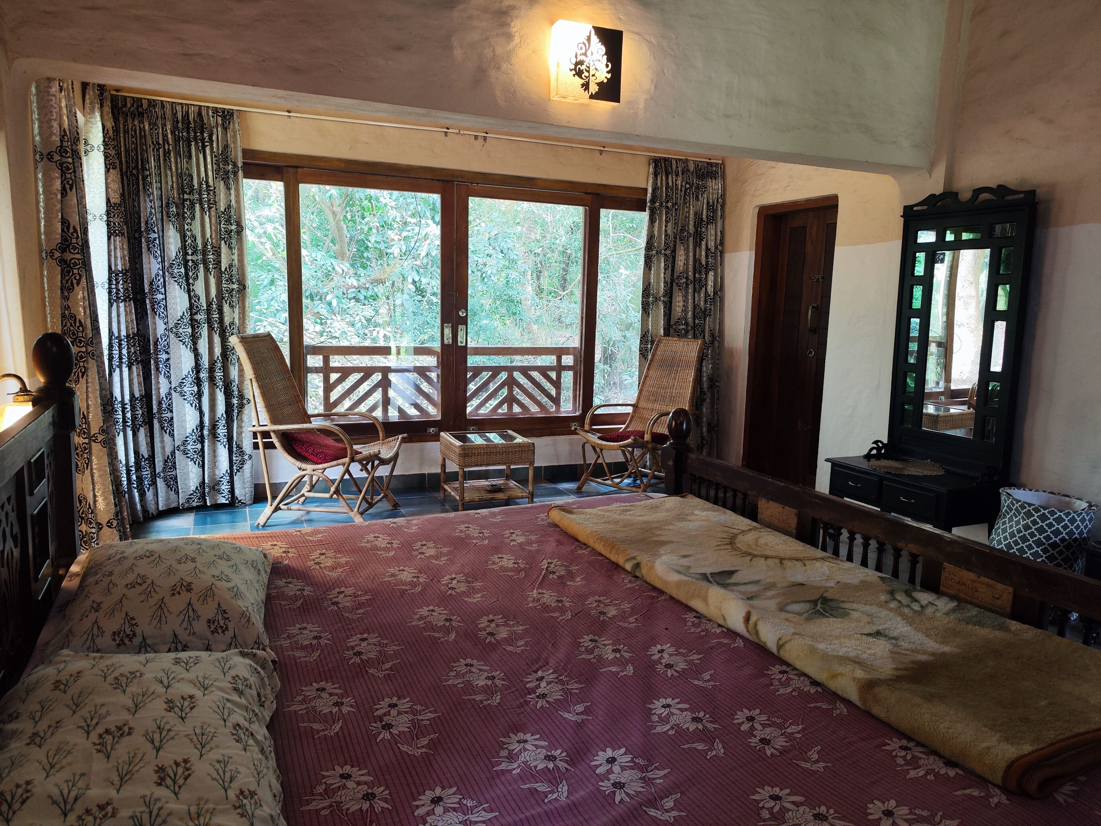 Una habitación con una cama, dos mecedoras, una mesita y un espejo.