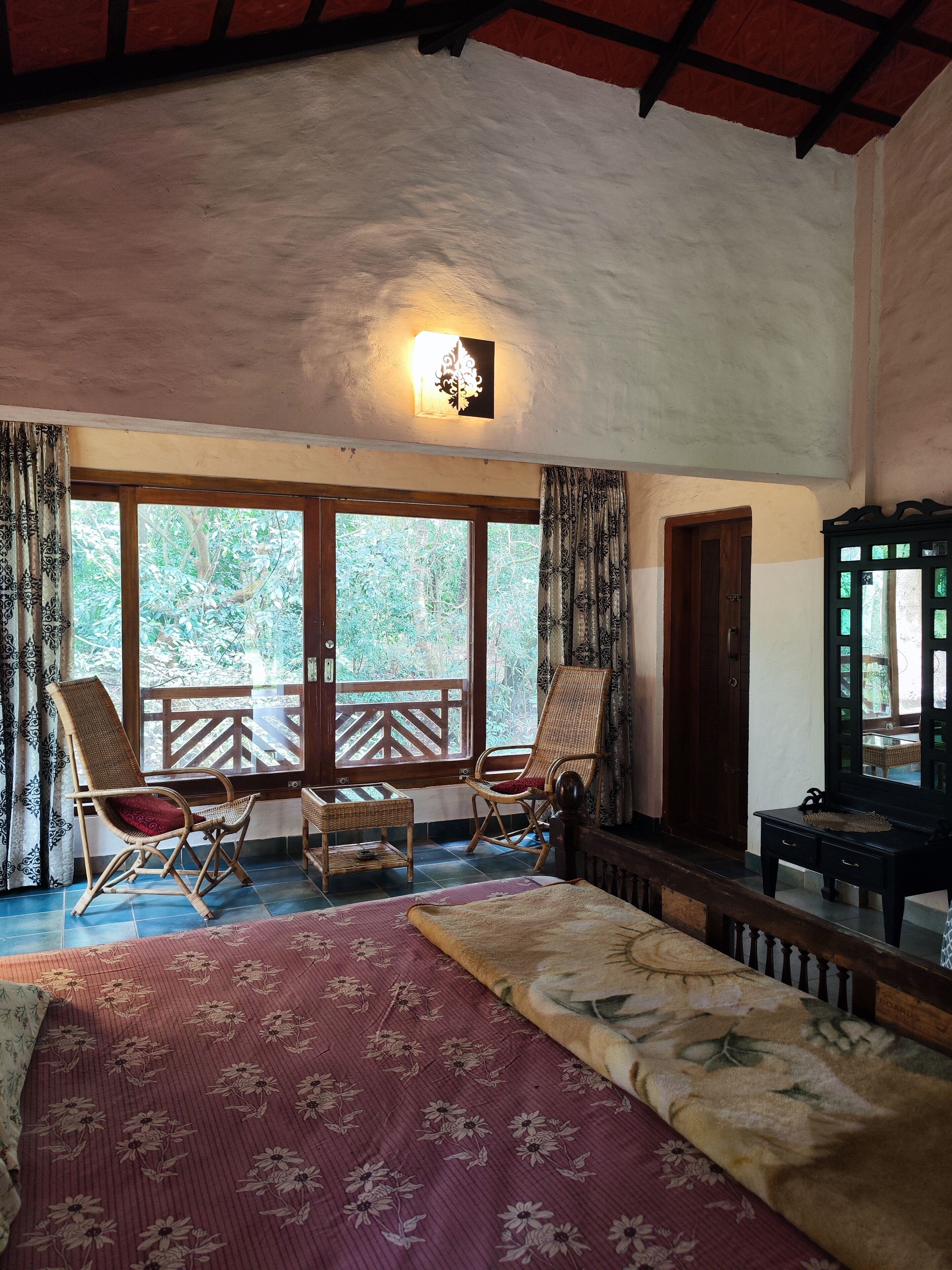 Ein Zimmer mit einem Bett, zwei Schaukelstühlen, einem kleinen Tisch und einem Spiegel.