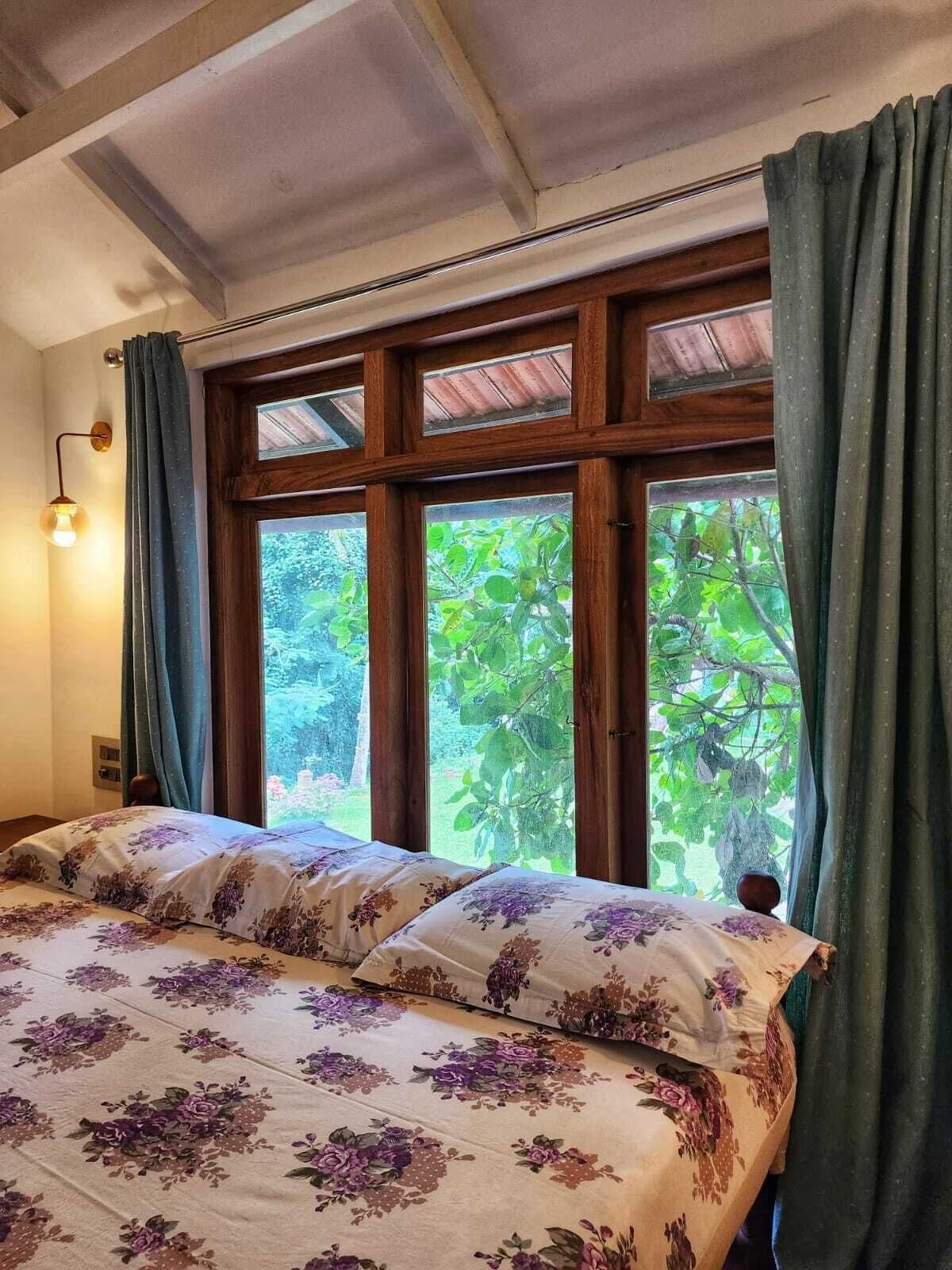 Une chambre à coucher avec un lit, une fenêtre avec des rideaux et un luminaire fixé au mur.