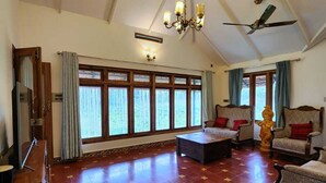 Ein geräumiges Wohnzimmer mit hoher Decke, großen Fenstern und einer Kristallleuchter.