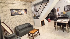 A living room with a sofa, a coffee table, a staircase, and a dining area. - Axon Cozy Modern House Blue Unit Near The Walking Street (Angeles City)