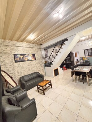 A living room with a sofa, a coffee table, a staircase, and a dining area.