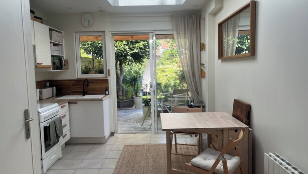 Eine kleine Küche mit Essbereich, einem Einbauofen und einem Fenster zum Garten hinaus.