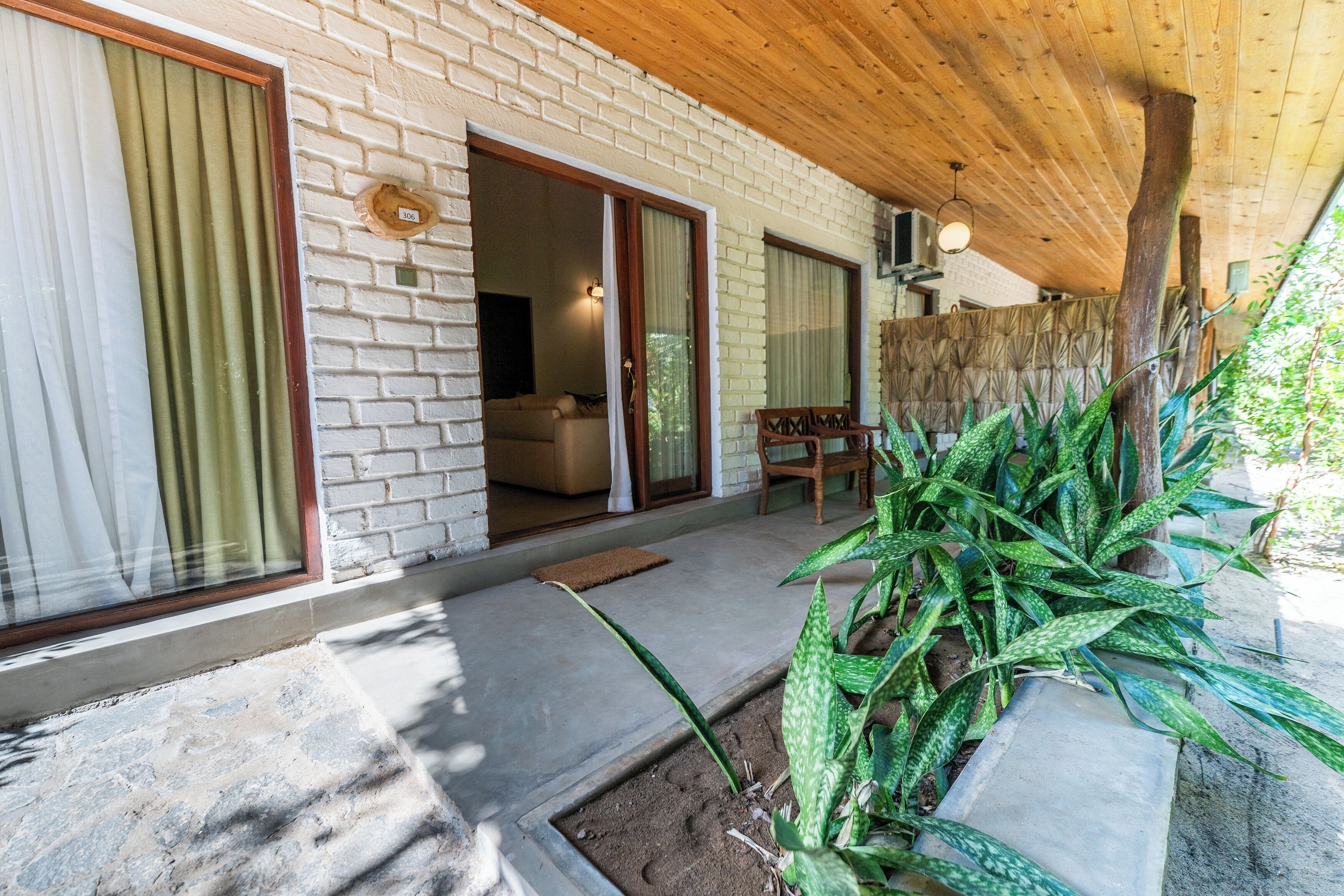 A covered outdoor area with a stone floor, a wooden ceiling, and a brick wall.