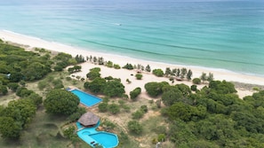 An aerial view of a beach resort with a swimming pool, a thatched-roof hut, and dense greenery. - Bellevue Beach Nilaveli BY PARADISE COLLECTION (Nilaveli)