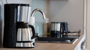 A coffee maker on a kitchen counter with a sink and a kettle in the background. - Apartment 'Stratmann' with Shared Terrace and Wi-Fi (Lennestadt)