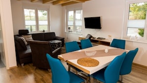 A modern living room with a sofa, chairs, a dining table, and a TV. - Apartment 'Stratmann' with Shared Terrace and Wi-Fi (Lennestadt)
