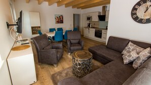 A modern living room with a sofa, armchairs, a coffee table, and a TV. - Apartment 'Stratmann' with Shared Terrace and Wi-Fi (Lennestadt)