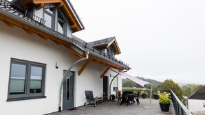 A modern building with a balcony, outdoor seating, and a view of the surrounding landscape. - Apartment 'Stratmann' with Shared Terrace and Wi-Fi (Lennestadt)