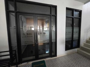 A hotel entrance with double doors and a welcome mat. - KEMARI Guesthouse Syariah (Semarang)