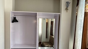 A room with a built-in wardrobe, a mirror, a brown sofa, and a wooden floor. - HOTEL JADE ARITHANG GANGTOK (Gangtok)