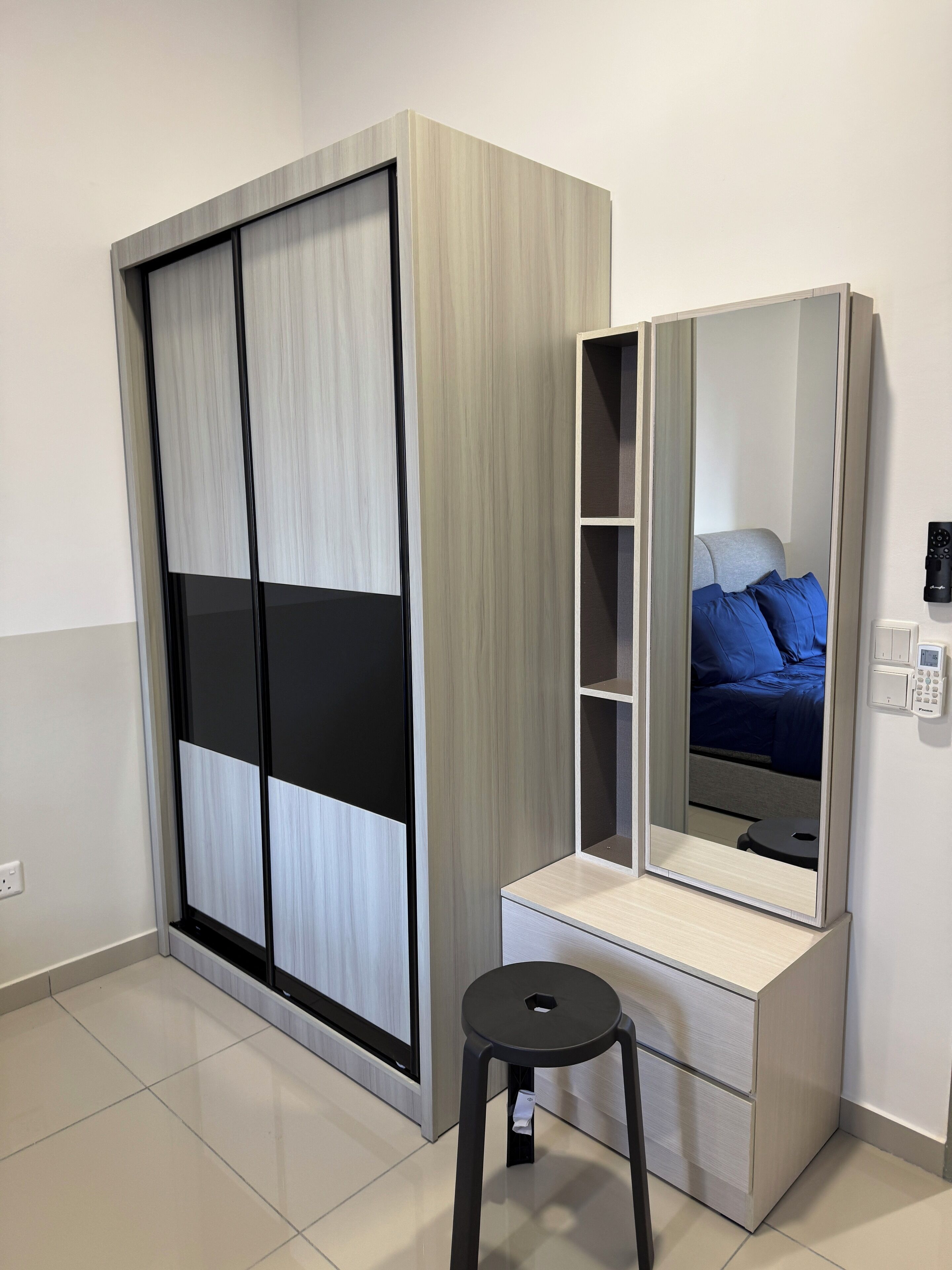 A modern bedroom with a wardrobe, a vanity with a mirror, and a stool.