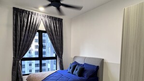 Une chambre à coucher avec un lit, un ventilateur de plafond, une fenêtre avec des rideaux et une vue sur les bâtiments à l’extérieur.