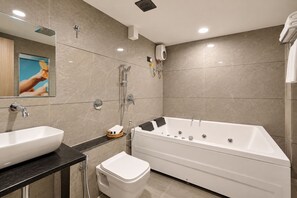 A modern bathroom with a bathtub, a toilet, a sink, and a shower. - HOTEL GRAND SHIVA (Ahmedabad)