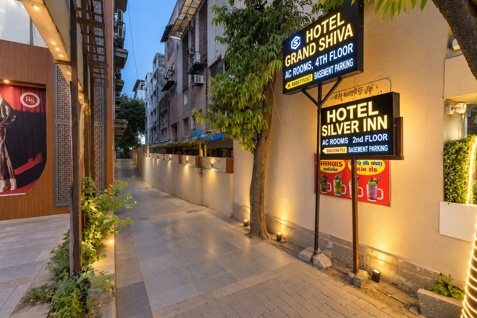 Un pasillo de hotel con indicaciones para Hotel Grand Shiva y Hotel Silver Inn, que señalan habitaciones con aire acondicionado en el cuarto y segundo piso respectivamente.