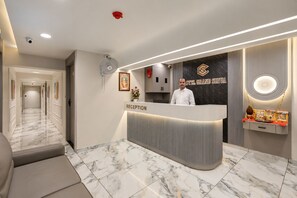 A hotel reception area with a marble floor, a reception desk, and a wall-mounted sign. - HOTEL GRAND SHIVA (Ahmedabad)