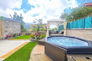 Eine Außenpatio mit Whirlpool, Korbmöbeln und einer Steinmauer.