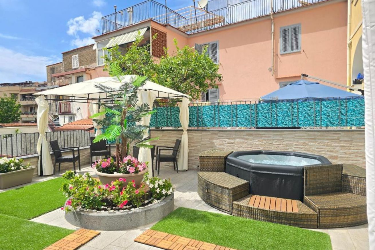 A patio with outdoor furniture, a hot tub, and a garden area with flowers.