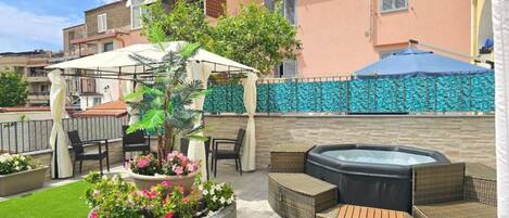 A patio with outdoor furniture, a hot tub, and a garden area with flowers.