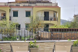 Un edificio residencial con balcones, un muro de piedra y una valla metálica.
