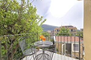 A balcony with a table and chairs, overlooking a cityscape and greenery. - Grazy Home | Private Terrace, Summer Pool & Relaxation in Vico Equense (Vico Equense)