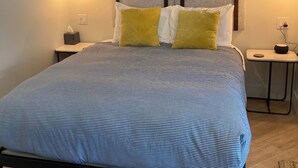 Un dormitorio con cama, dos lámparas de noche, una mesita de noche y cabecero.