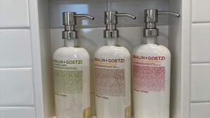 A shelf with three bottles of Malin+Goetz hair care products. - Great Island Inn - Standard Queen Guest Room (New Castle)