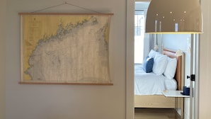 Une pièce avec une grande carte accrochée au mur, un lit avec une literie blanche, une table de chevet et une lampe suspendue.