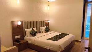 Una cama bien hecha con cabecera, lámparas de noche y una mesita de noche con un teléfono.